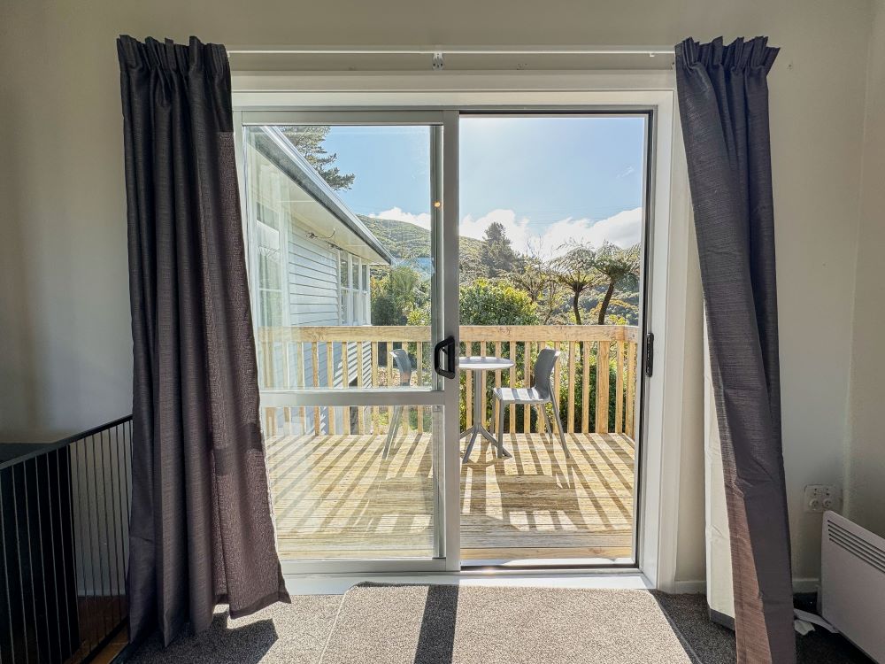 The deck of the house has two chairs and a small table, and looks out to an incredible view of the park