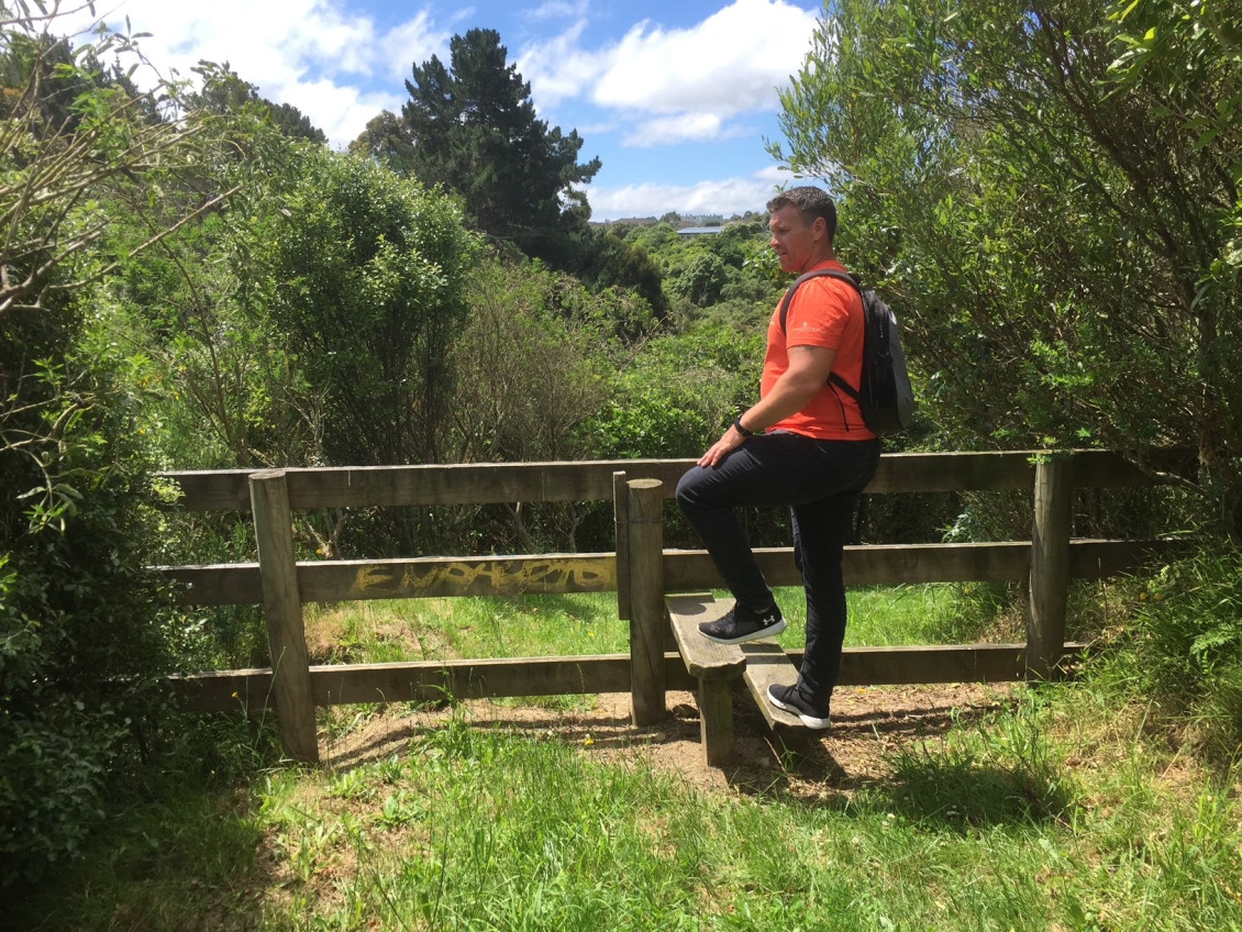 Person climbing a stile in Belmont Park