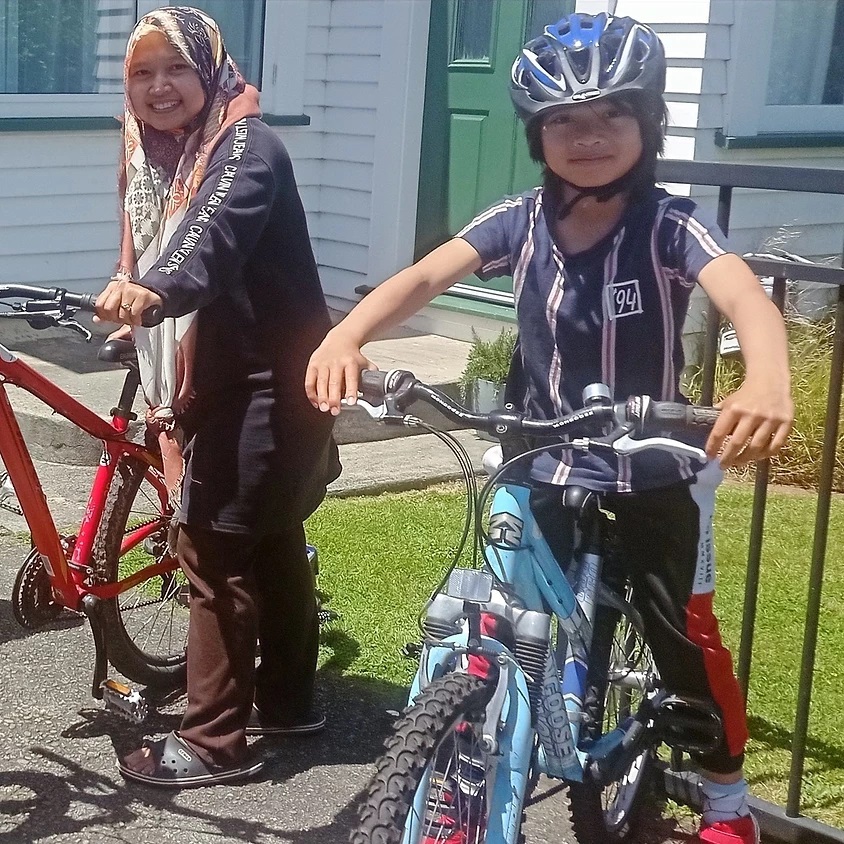 Two people straddling bikes smile at the camera