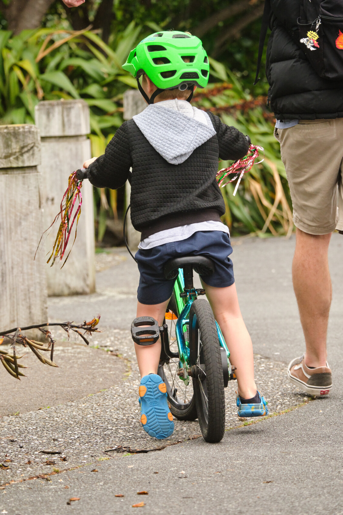 A small child in a helmet and on a bike with tasseled handlebars